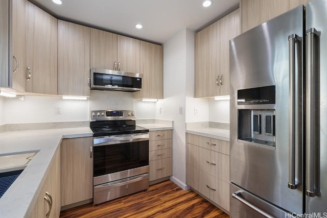 kitchen with light stone counters, dark hardwood / wood-style flooring, light brown cabinetry, and appliances with stainless steel finishes