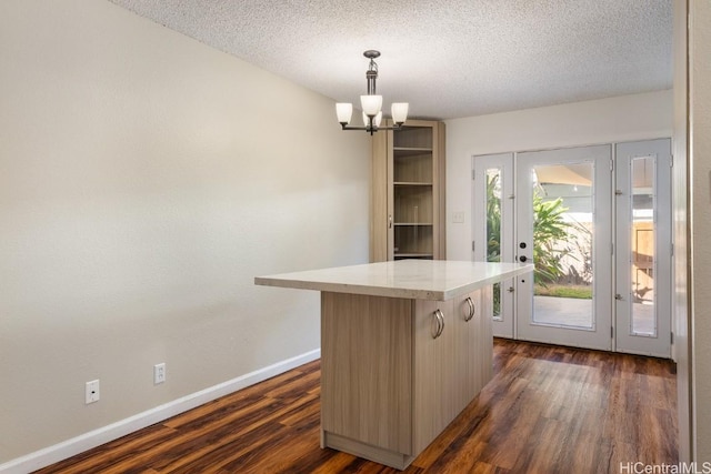 kitchen with decorative light fixtures, a textured ceiling, a center island, dark hardwood / wood-style floors, and a chandelier