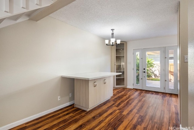 interior space with vaulted ceiling with beams, an inviting chandelier, dark wood-type flooring, and a textured ceiling