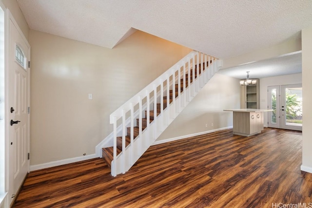 entrance foyer with a textured ceiling, a chandelier, and dark hardwood / wood-style flooring