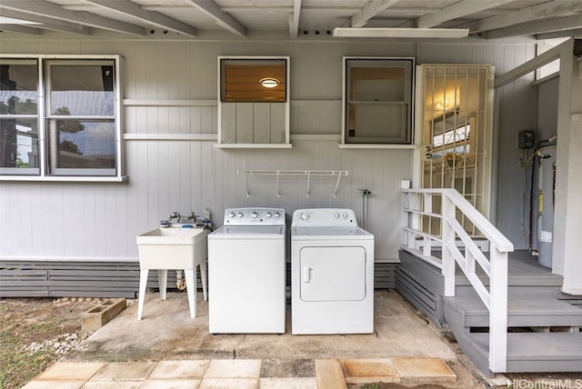 washroom with sink, wood walls, and washing machine and dryer