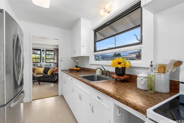 kitchen featuring sink, white cabinetry, stainless steel fridge, and light carpet