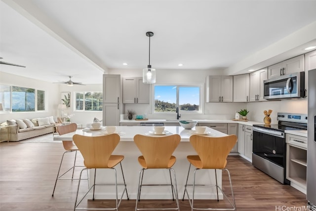 kitchen with appliances with stainless steel finishes, gray cabinets, and a kitchen island