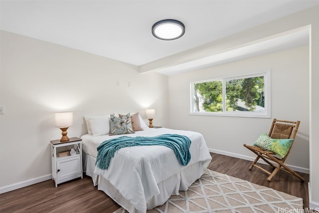 bedroom with dark wood-type flooring and beam ceiling