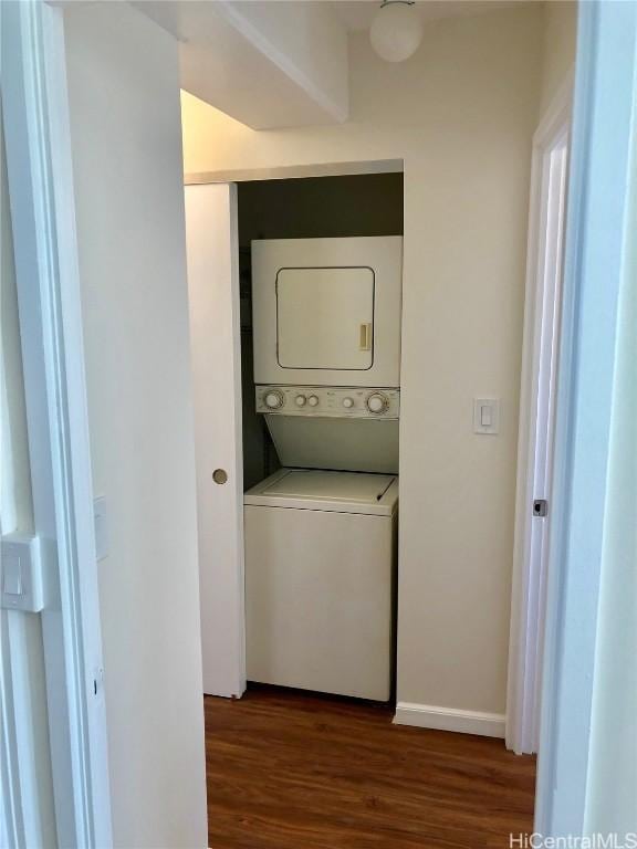 clothes washing area featuring stacked washer / dryer and dark wood-type flooring