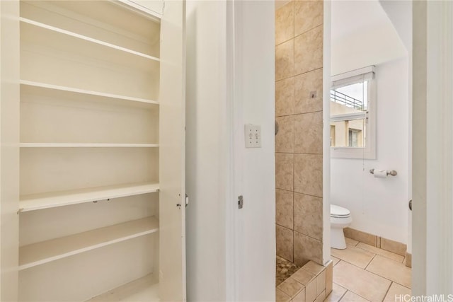 bathroom featuring toilet, tile patterned flooring, and a shower