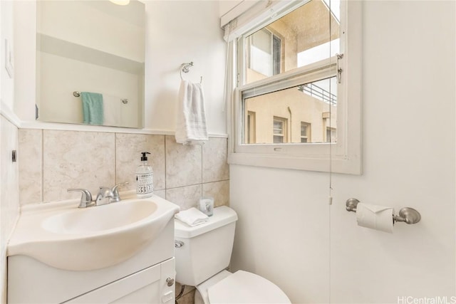 bathroom featuring toilet, tasteful backsplash, tile walls, and vanity