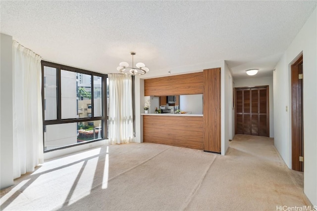 kitchen with light colored carpet, hanging light fixtures, a textured ceiling, and a notable chandelier