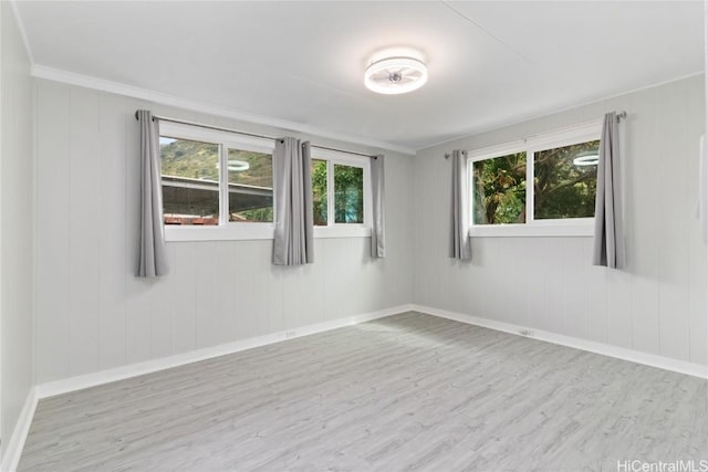 empty room with ornamental molding and light hardwood / wood-style floors