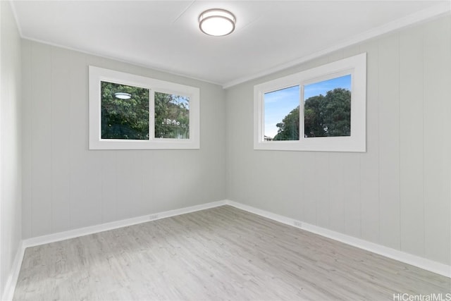 spare room featuring ornamental molding, plenty of natural light, and light hardwood / wood-style flooring