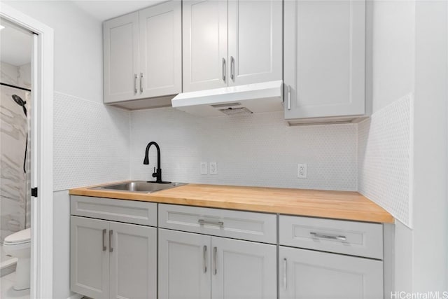 kitchen with tasteful backsplash, sink, gray cabinetry, and wood counters