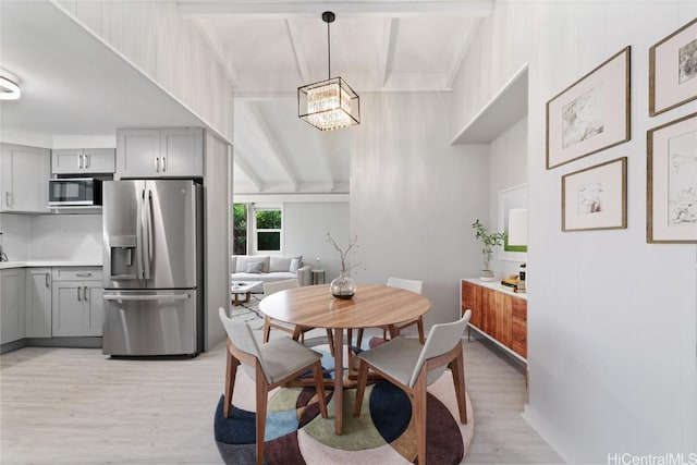 dining area featuring beamed ceiling, an inviting chandelier, and light wood-type flooring