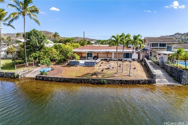 back of property featuring a water and mountain view and a hot tub