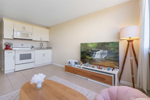 kitchen with sink, white appliances, light tile patterned floors, and white cabinets