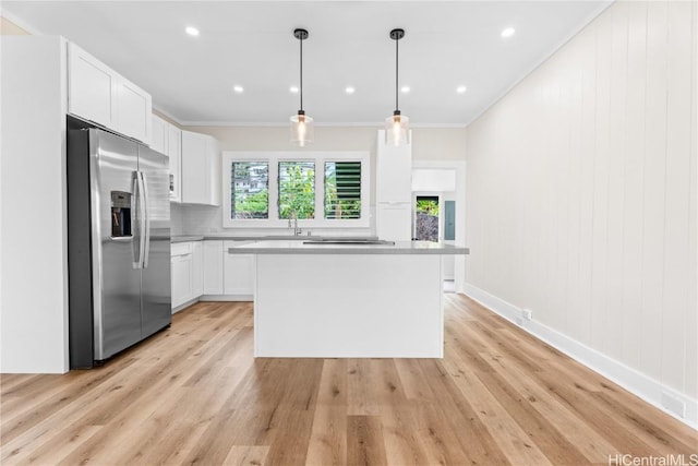 kitchen featuring stainless steel fridge with ice dispenser, white cabinetry, a kitchen island, ornamental molding, and pendant lighting