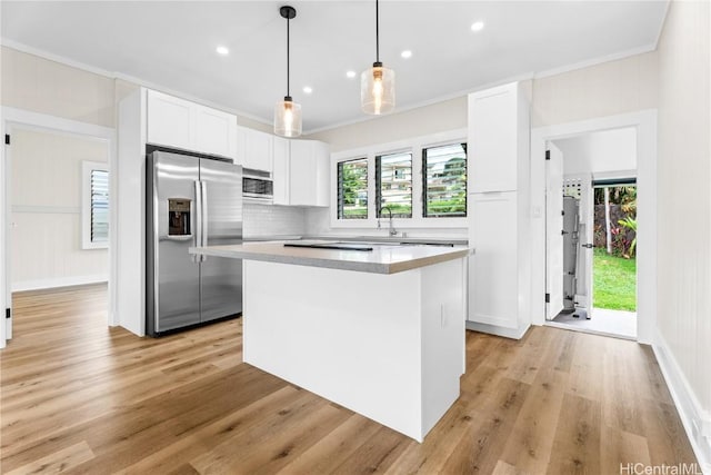 kitchen featuring decorative light fixtures, white cabinetry, a center island, and stainless steel appliances