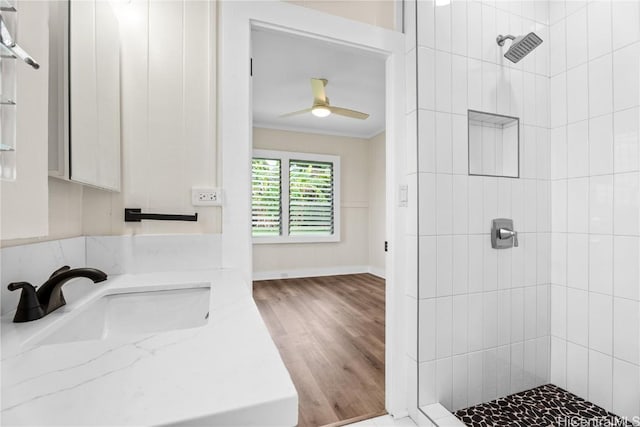 bathroom featuring vanity, ceiling fan, ornamental molding, and a tile shower