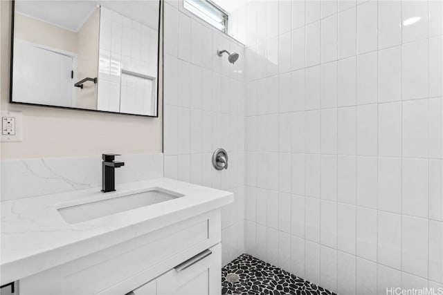 bathroom with a tile shower and vanity