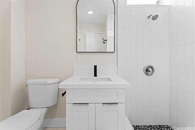 bathroom with a tile shower, toilet, and vanity