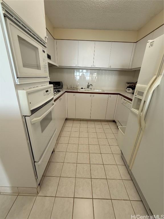 kitchen with white cabinetry, white appliances, sink, and light tile patterned floors