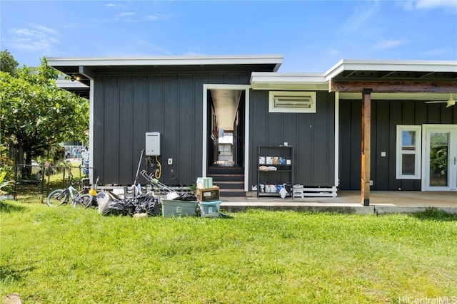 rear view of house featuring a yard, fence, and board and batten siding