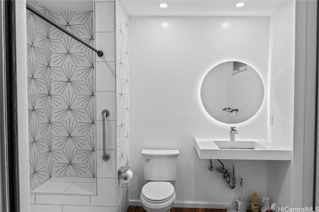 bathroom with a tile shower, recessed lighting, toilet, and baseboards