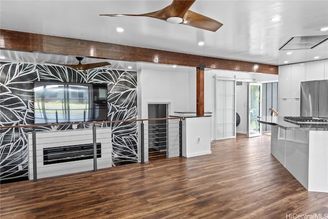 kitchen featuring dark countertops, wood finished floors, freestanding refrigerator, a barn door, and modern cabinets