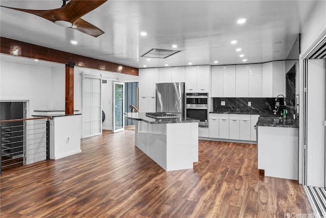 kitchen featuring modern cabinets, a barn door, dark wood-type flooring, and appliances with stainless steel finishes