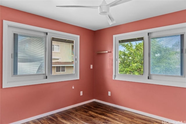 empty room featuring baseboards, a ceiling fan, and dark wood-style flooring