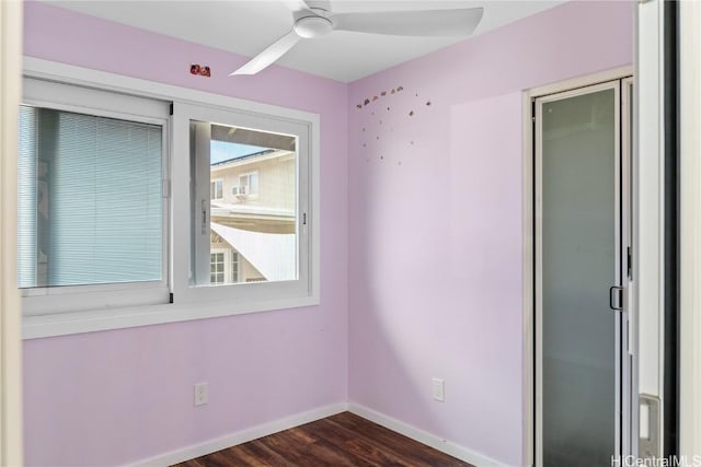 spare room with baseboards, dark wood-type flooring, and ceiling fan