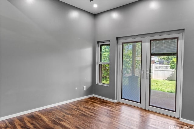 unfurnished room featuring french doors, baseboards, and wood finished floors