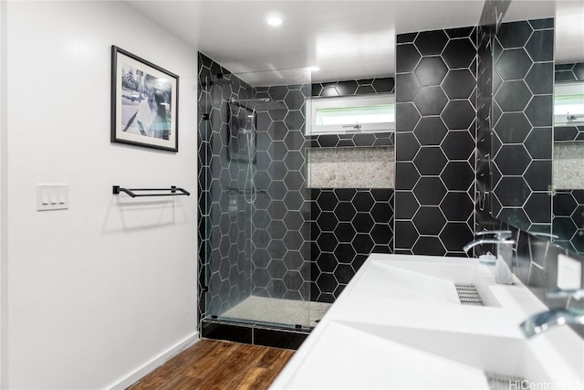 bathroom with a tile shower, baseboards, and wood finished floors