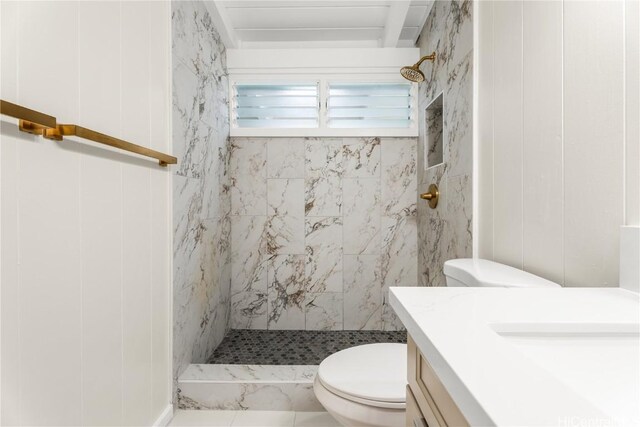 bathroom with tiled shower, toilet, and vanity