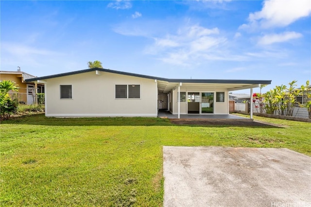 rear view of house with a lawn and a carport