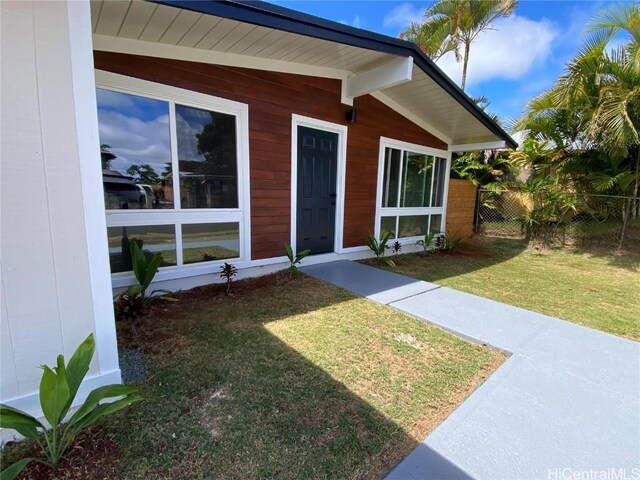 view of exterior entry featuring a lawn