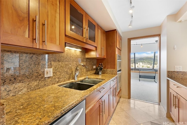 kitchen with sink, light tile patterned floors, backsplash, light stone counters, and stainless steel dishwasher