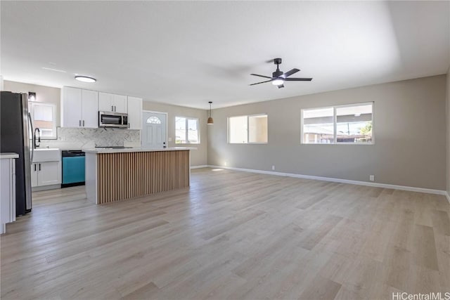 kitchen with decorative light fixtures, white cabinets, a center island, and appliances with stainless steel finishes