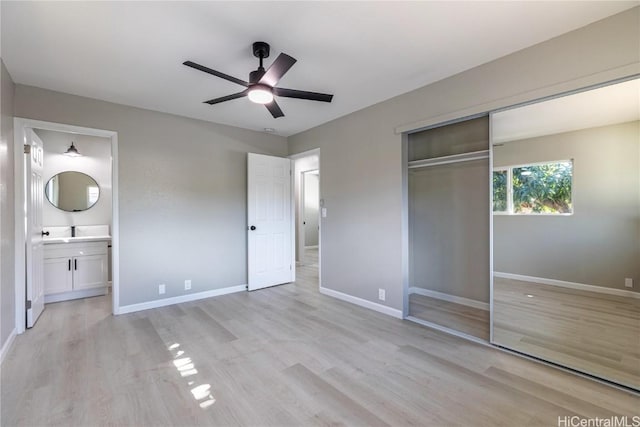 unfurnished bedroom featuring light wood-type flooring, ceiling fan, connected bathroom, and a closet