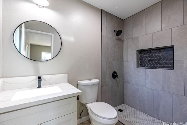 bathroom featuring vanity, toilet, and a tile shower