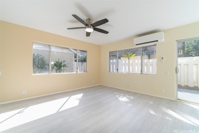 empty room featuring light wood-type flooring, ceiling fan, a wealth of natural light, and a wall mounted AC