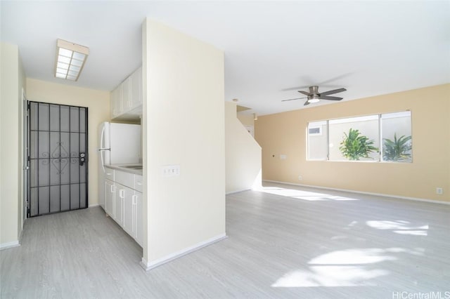 interior space featuring white cabinets, light wood-type flooring, and ceiling fan