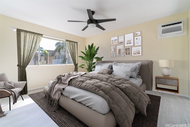 bedroom featuring ceiling fan, light hardwood / wood-style flooring, and a wall mounted air conditioner