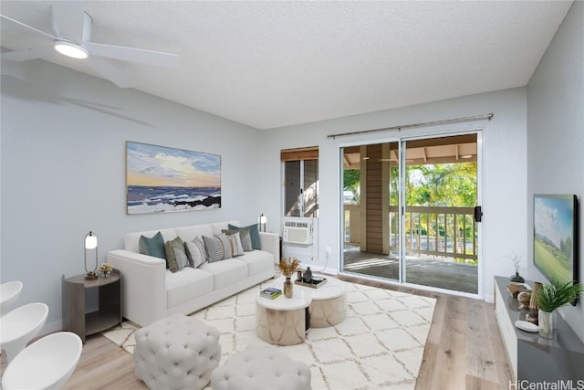 living room featuring light hardwood / wood-style floors, a textured ceiling, and ceiling fan