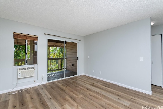 spare room with light wood-type flooring, a textured ceiling, and cooling unit