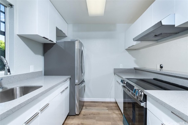 kitchen featuring wall chimney range hood, stainless steel appliances, and white cabinets