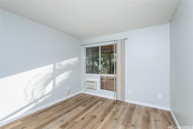 spare room featuring light wood-type flooring and a textured ceiling