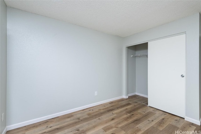 unfurnished bedroom featuring light hardwood / wood-style floors, a textured ceiling, and a closet