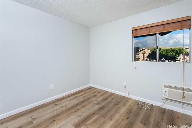 spare room with wood-type flooring, a textured ceiling, and a wall mounted air conditioner