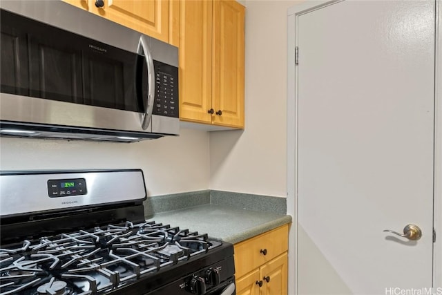 kitchen with gas range oven and light brown cabinets