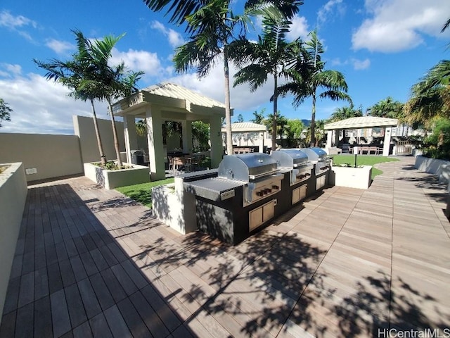 wooden deck featuring a gazebo, grilling area, and exterior kitchen